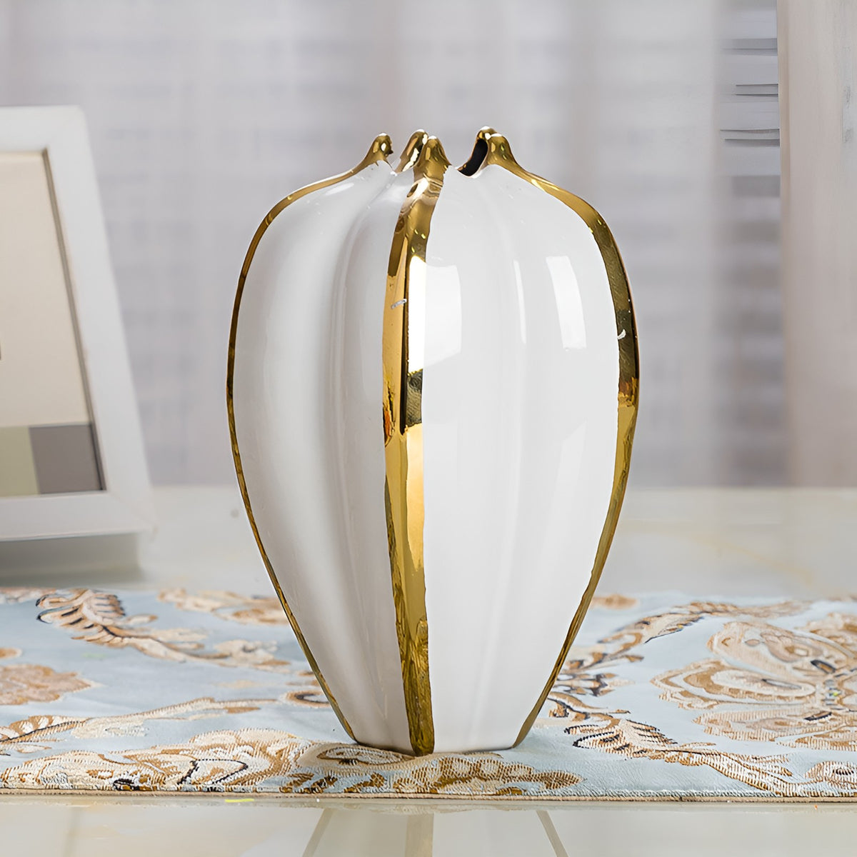 Modern white glazed ceramic vase with gold trimmed ridges on tabletop