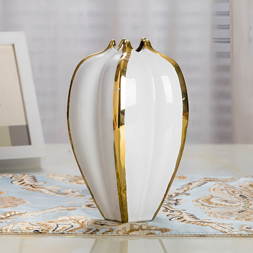 Modern white glazed ceramic vase with gold trimmed ridges on tabletop