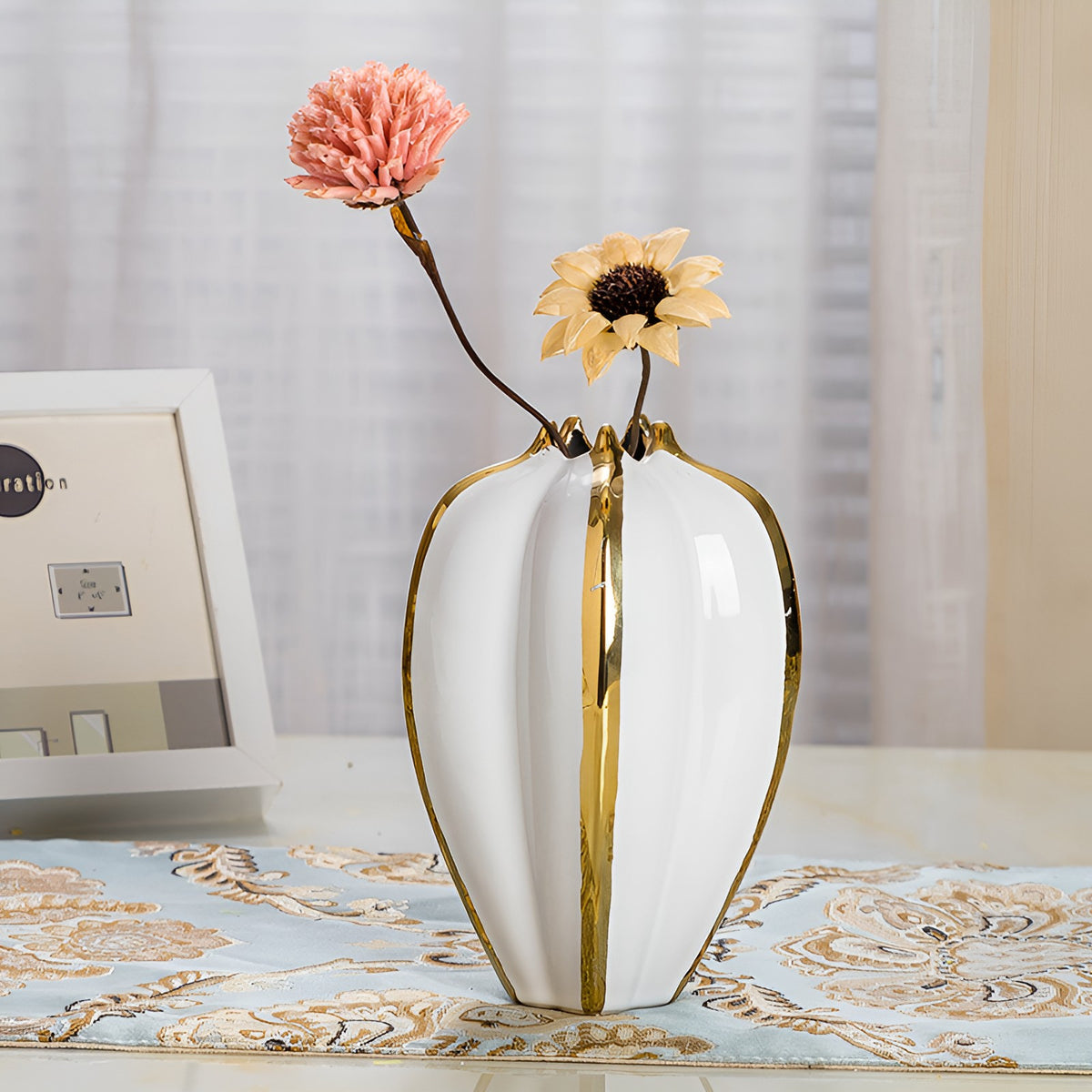 White and gold ribbed ceramic vase styled with artificial flowers on table